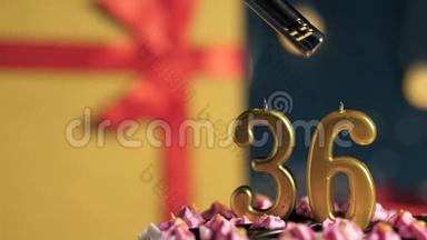 生日蛋糕36号金色蜡烛用打火机点燃，蓝色背景礼品黄色盒子用红丝带系好